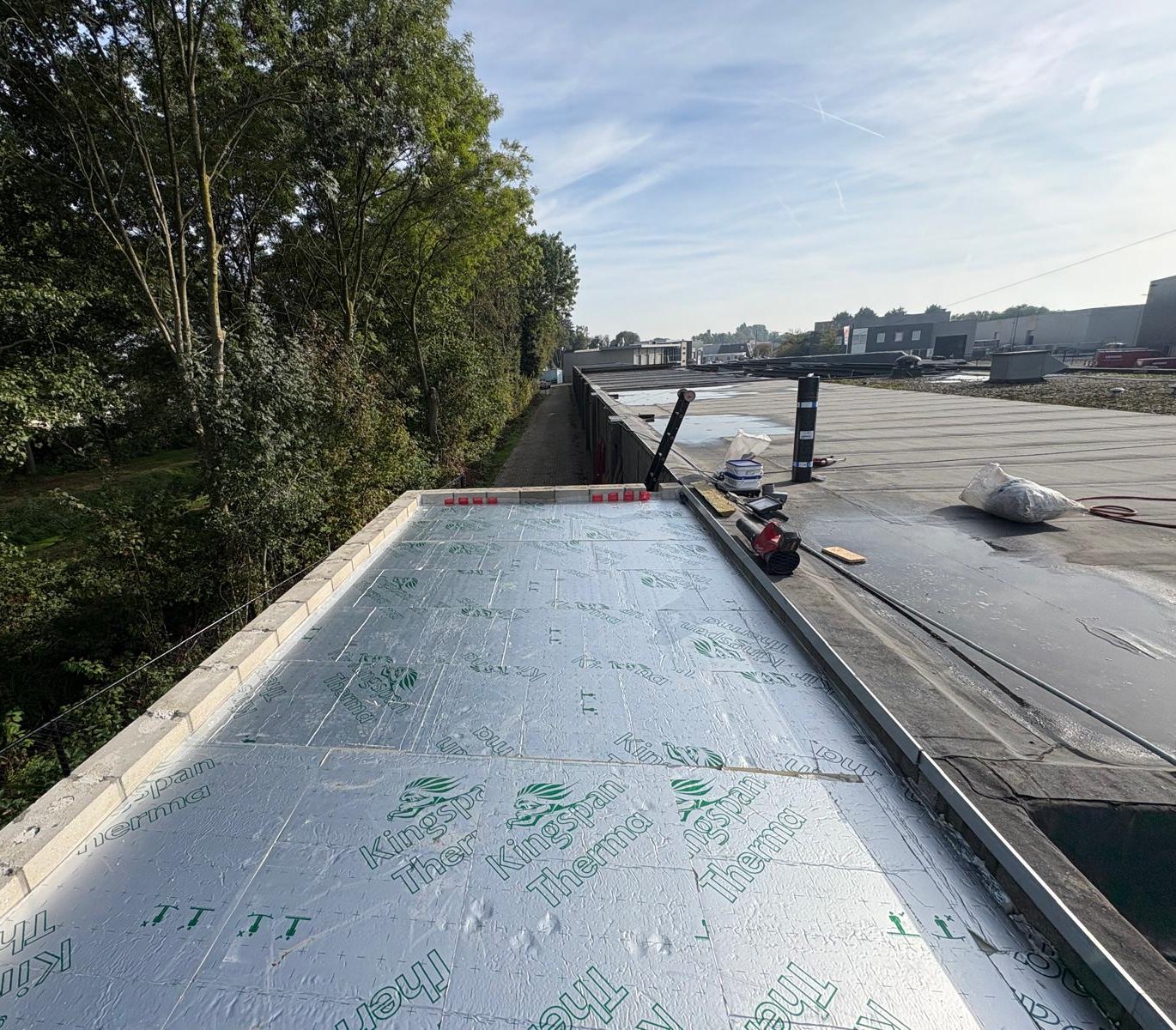 Nieuw gelegde isolatieplaten op een plat dak naast een al afgewerkt deel met bitumen